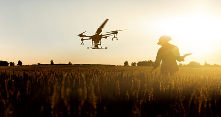 Fototapeta na wymiar Farmer controls drone sprayer with a digital tablet