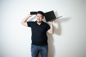 Young Asian in black polo Holding a smartphone and laptop
In a white background