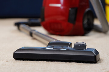 Red vacuum cleaner on a beige carpet