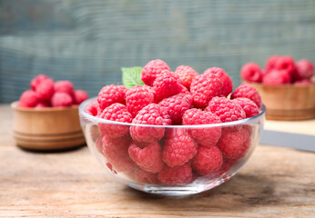 Delicious fresh ripe raspberries in bowl on wooden table
