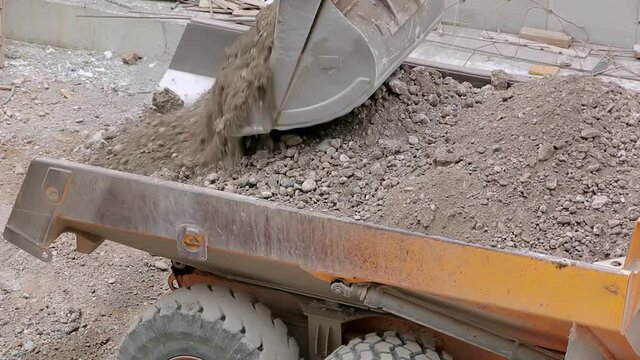 Excavator loads the earth into a dump truck. Work on the construction site