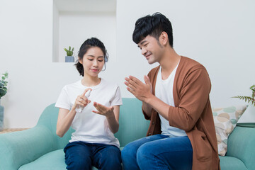 Asian couple using sanitizer alcohol gel to washing hand for prevent viruses and bacteria at home.