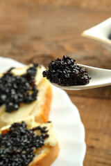 Spoon with black caviar in female caviar over caviar.