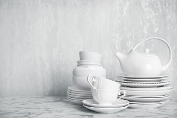 Set of clean tableware on white marble table. Space for text