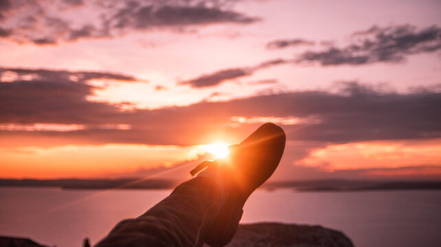 silhouette of a man sitting on a rock at sunset