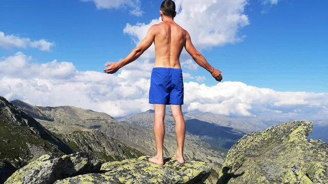 man stands on top of a mountain with open hands. at the top of the mountain, a man with his arms spread wide.