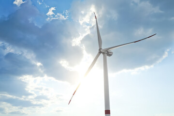 Modern windmill against sky with clouds, low angle view. Energy efficiency