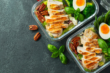 Healthy meal prep containers with green beans, chicken breast and broccoli. A set of food for keto diet in lunchbox on a dark concrete background. Top view with copy space