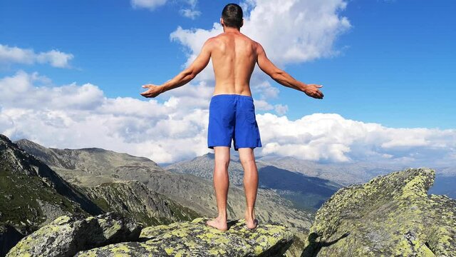 man stands on top of a mountain with open hands. at the top of the mountain, a man with his arms spread wide.