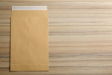 Kraft paper envelope on wooden background, top view. Space for text