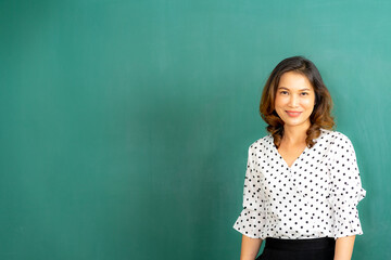 Asian teacher at the board with books in preschool copy space on background