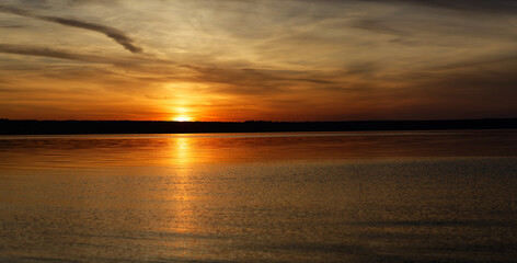 Obraz premium Golden sunset on the sea shore. View from the water to the shore.