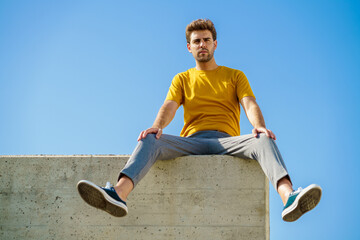 Man sitting on a ledge looking around
