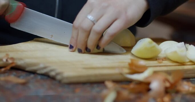 Woman's hands cutting an onion at home with painted nails / Warm house vibes / cooking at home / 4k at 60fps (slowmotion)