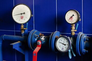 Round pressure gauges are against a bright blue wall
