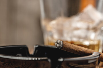 Lighted cigar in an ashtray close up