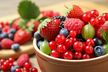 Mix of different fresh berries in bowl on table, closeup