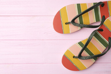 Flip flops and space for text on pink wooden background, top view. Beach objects