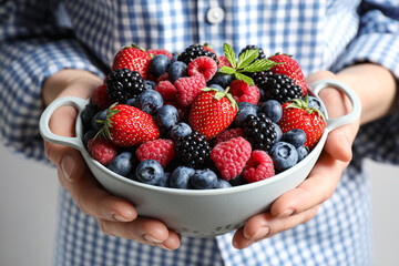 Woman with bowl of delicious summer berries, closeup
