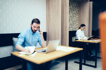 Man making phone call and notes near woman with notepad