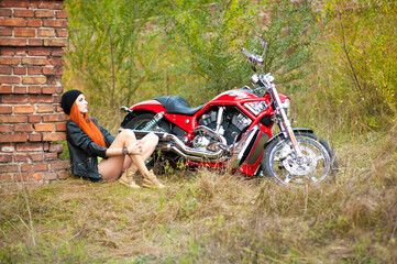 Plakat Portrait of charming young woman with red hair near a motorcycle