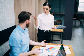 Concentrated colleagues discussing account and surfing laptop