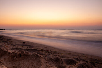 Obraz premium Seascape. Waves and surf. Sunset and dawn at sea. Calm on the ocean. Beautiful sky and clouds illuminated by the sun. Natural background. Summer time. Long exposure blurred water movement.