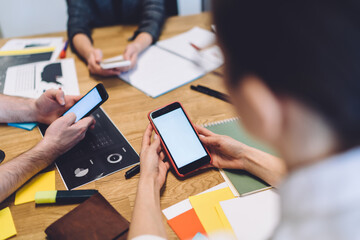 Adult employees interacting with smartphones in workplace