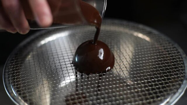 Melted chocolate falling in slow motion on scoop of ice cream.