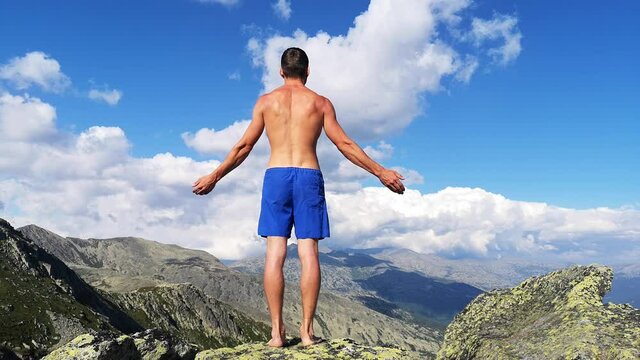man stands on top of a mountain with open hands. at the top of the mountain, a man with his arms spread wide.