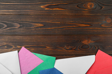 Fototapeta na wymiar Colorful paper envelopes on wooden background, flat lay. Space for text