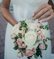 Obraz na płótnie Canvas bride's hand with an elegant wedding ring with white gold diamonds on a bouquet of their peonies