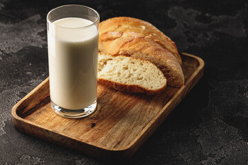 Glass of milk with sliced baguette on wooden board