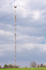 The telecommunications tower, located at the top of the hill, rises in the sky against the blue sky.