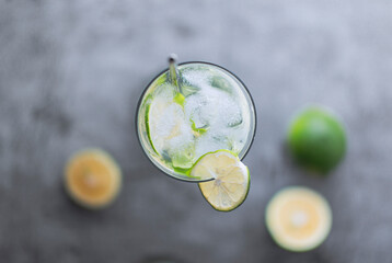 Flat lay top view of cold refreshing beverage with sliced lime ripes and ice reverse light image in studio with white illuminated background