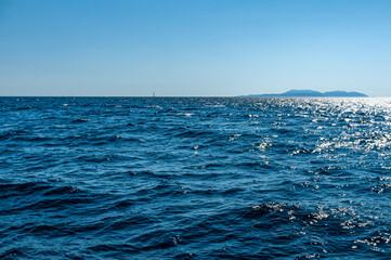 Deep blue sea horizon. Waves on the sea with island on horizon.
