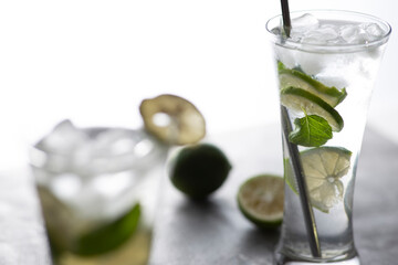Cold refreshing beverage with sliced lime ripes and ice reverse light image in studio with white illuminated background