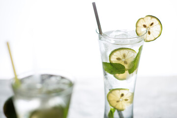 Cold refreshing beverage with sliced lime ripes and ice reverse light image in studio with white illuminated background