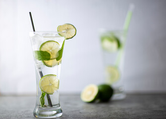 Cold refreshing beverage with sliced lime ripes and ice reverse light image in studio with white illuminated background
