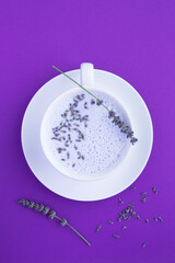 Top view of lavender moon milk in the white cup on the violet surface.  Location vertical.