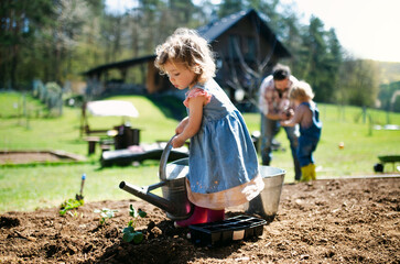 Small girl watering outdoors in garden, sustainable lifestyle concept. © Halfpoint