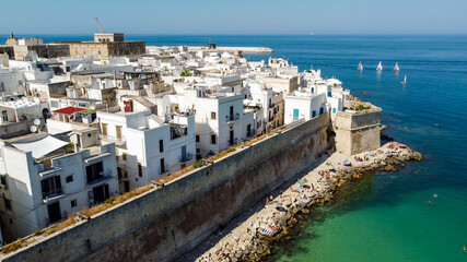 Fototapeta na wymiar Aerial view of Monopoli in Apulia, south of Italy - Ancient walls protecting the city with stone breakwater where tourists like to swim and enjoy their holidays in the sun