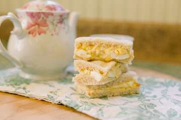 English Tea Sandwich (egg sandwich) with a white and pink tea pot in the background.