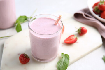 Tasty milk shake with strawberries and mint on white marble board