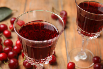Delicious cherry wine with ripe juicy berries on wooden table, closeup