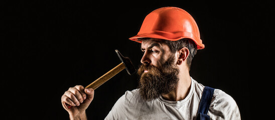 Bearded builder isolated on black background. Hammer hammering. Builder in helmet, hammer,...