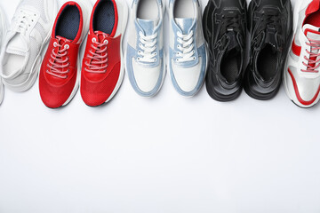 Many stylish sneakers on white background, top view