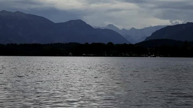 Gewitter &uuml;ber den Bergen und im Vordergrund ein See vor der Alpenkulisse
