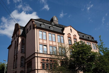 Schönes altes Schulgebäude der IGS Nordend vor blauem Himmel mit weißen Wolken im Sommer bei...