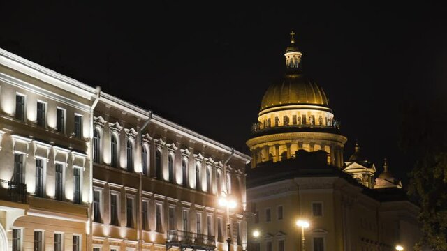 Historical building with lighting on background of Cathedral at night. Action. Beautiful old architecture glows at night. Dome of Cathedral is brightly lit in night